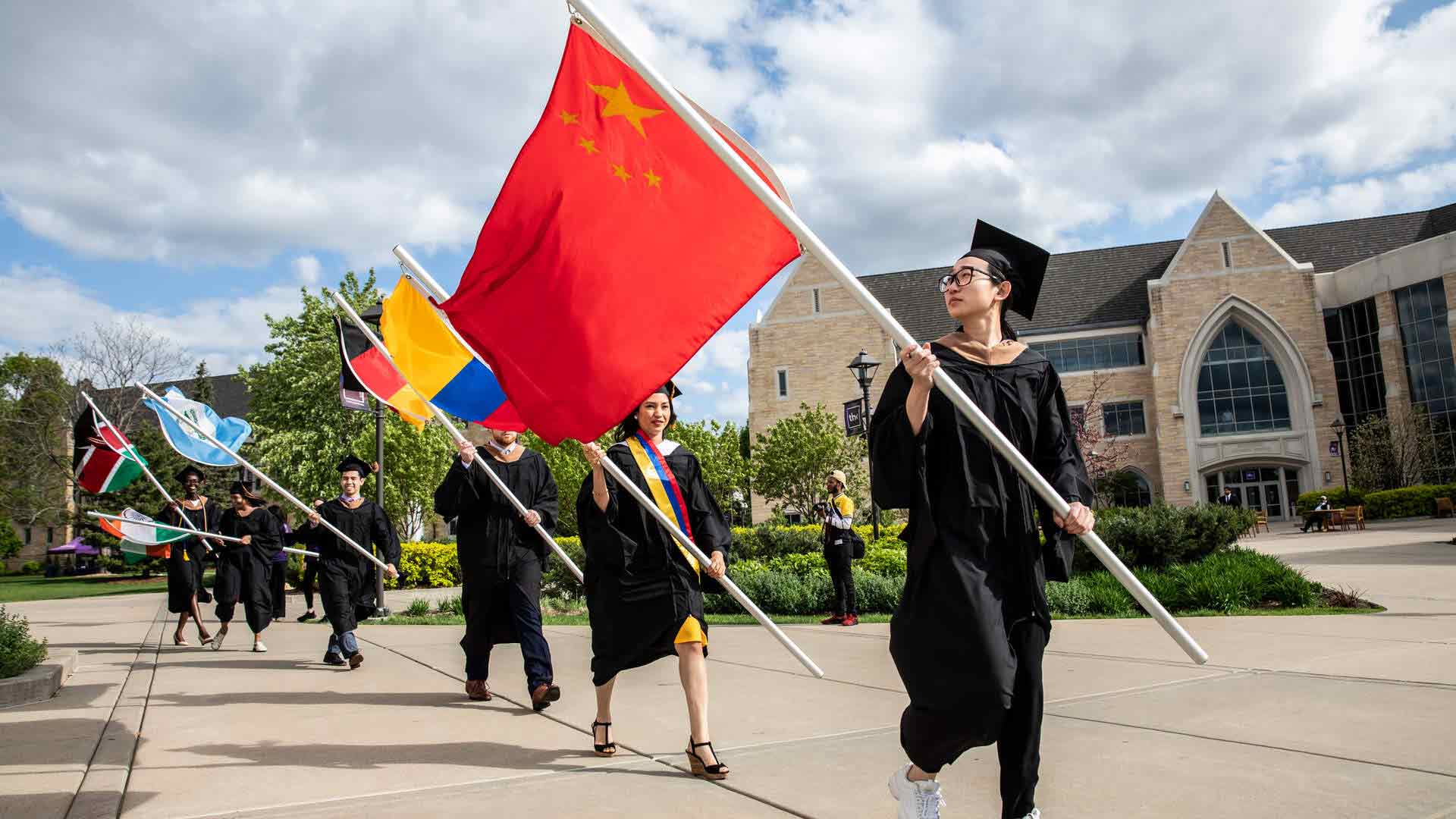International students carry their flag at graduation.