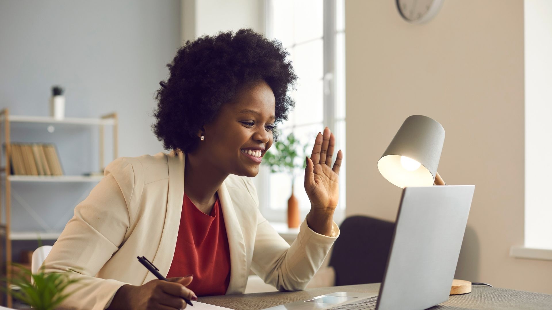 smiling woman waves during an online meeting