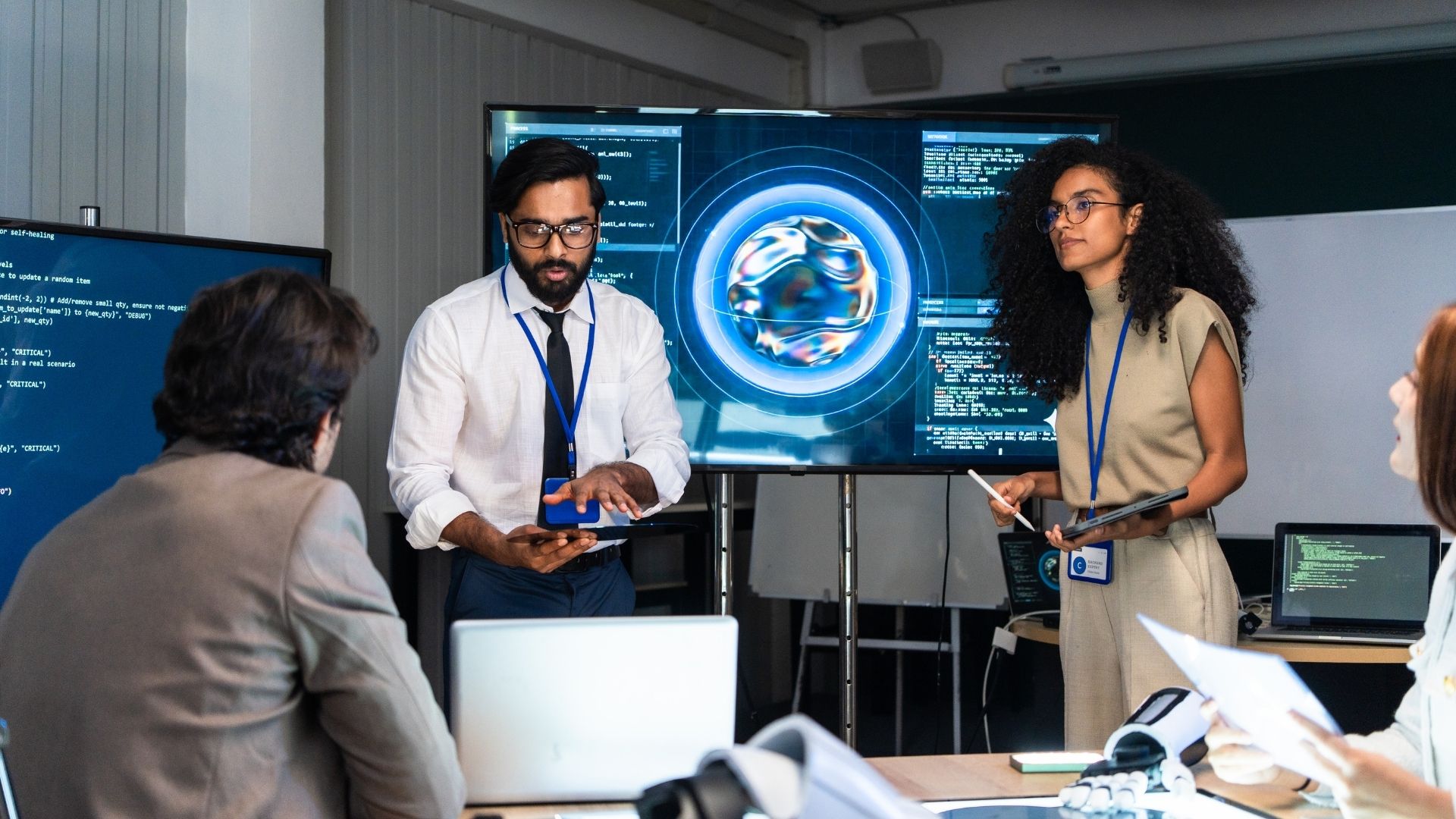 Individuals give a presentation in front of a video screen.