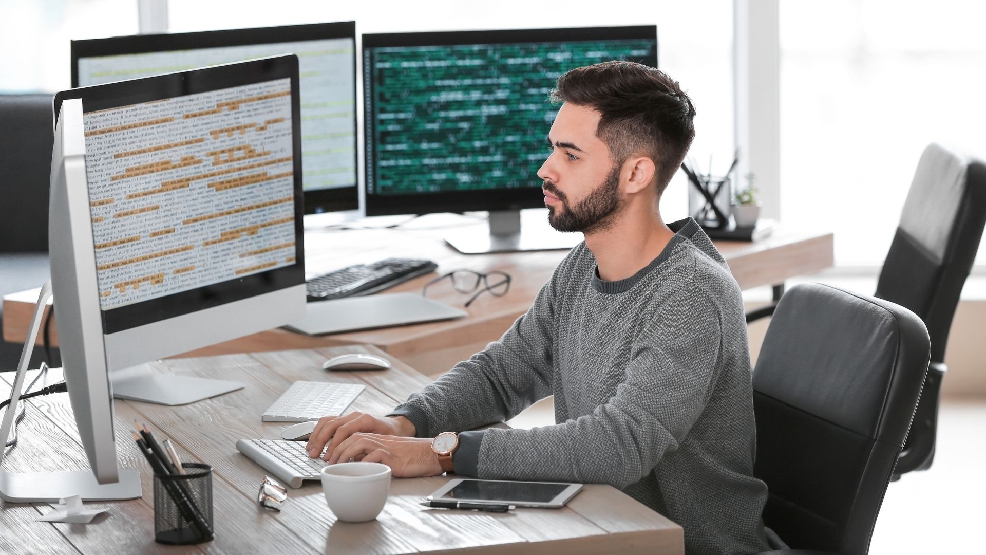 man sits in front of computer looking at code