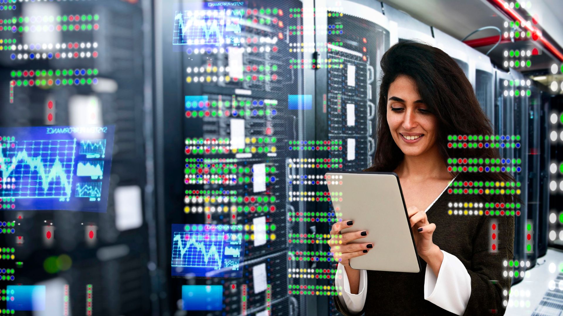 A woman standing in a server room looking at a device.