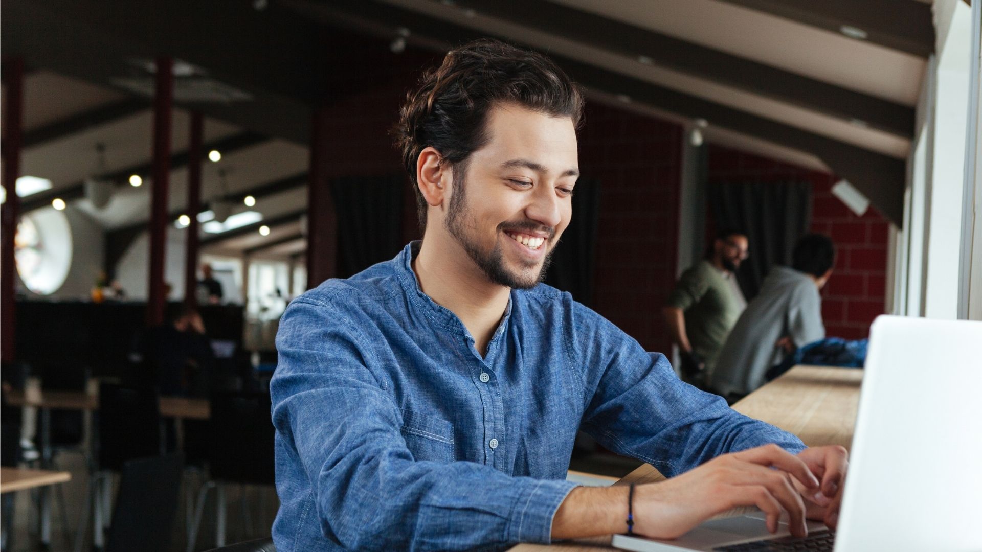 Graduate student sitting in front of computer screen smiles.