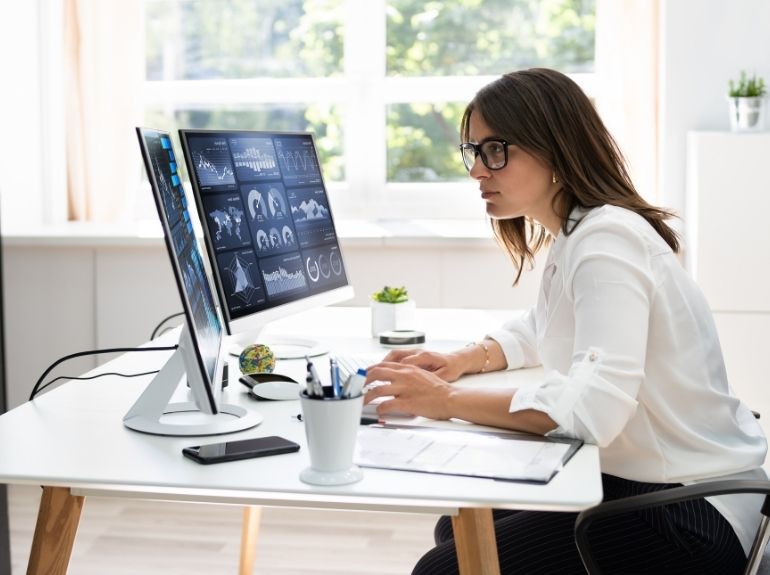 Individual works in front of two computers.